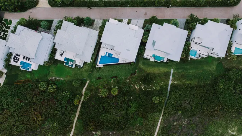 Aerial view of white-roofed homes with pools