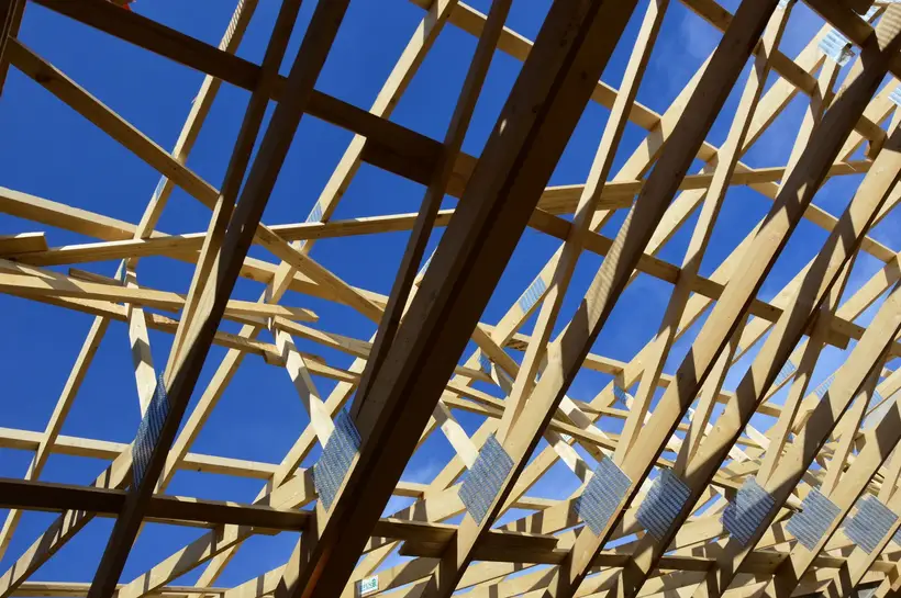 Wooden roof trusses against a blue sky