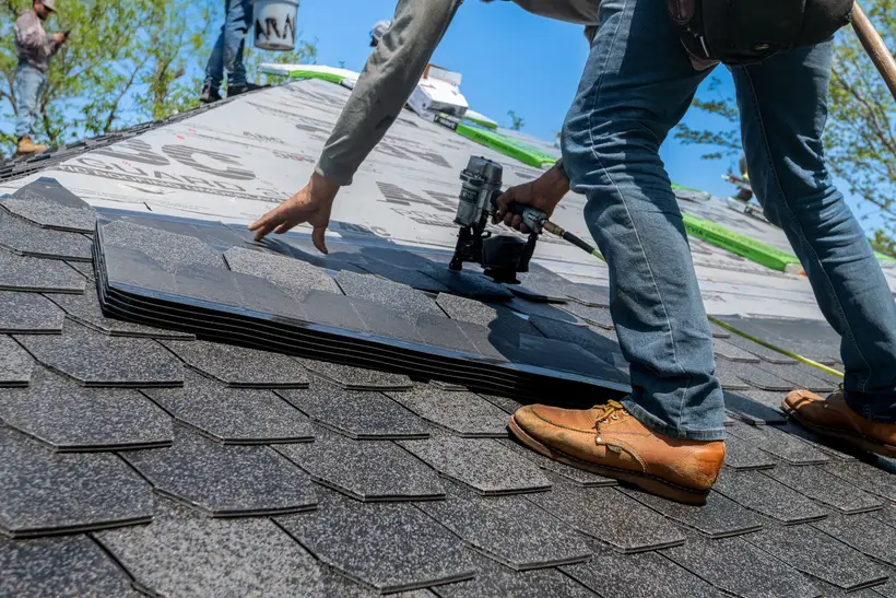 Roofer setting a shingle with a nail gun