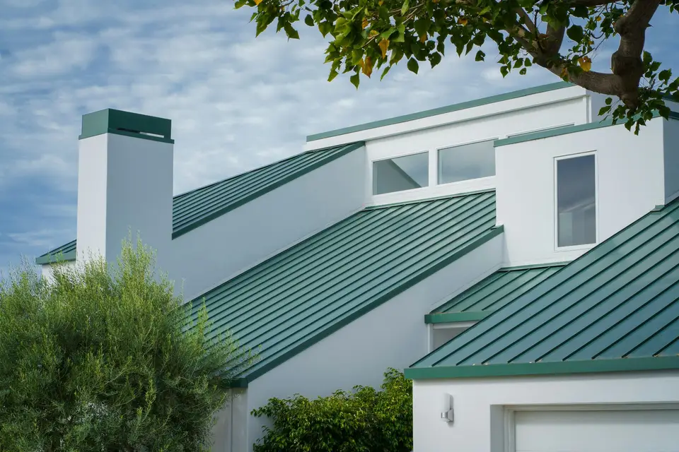 Green standing seam roofs on a white modern home