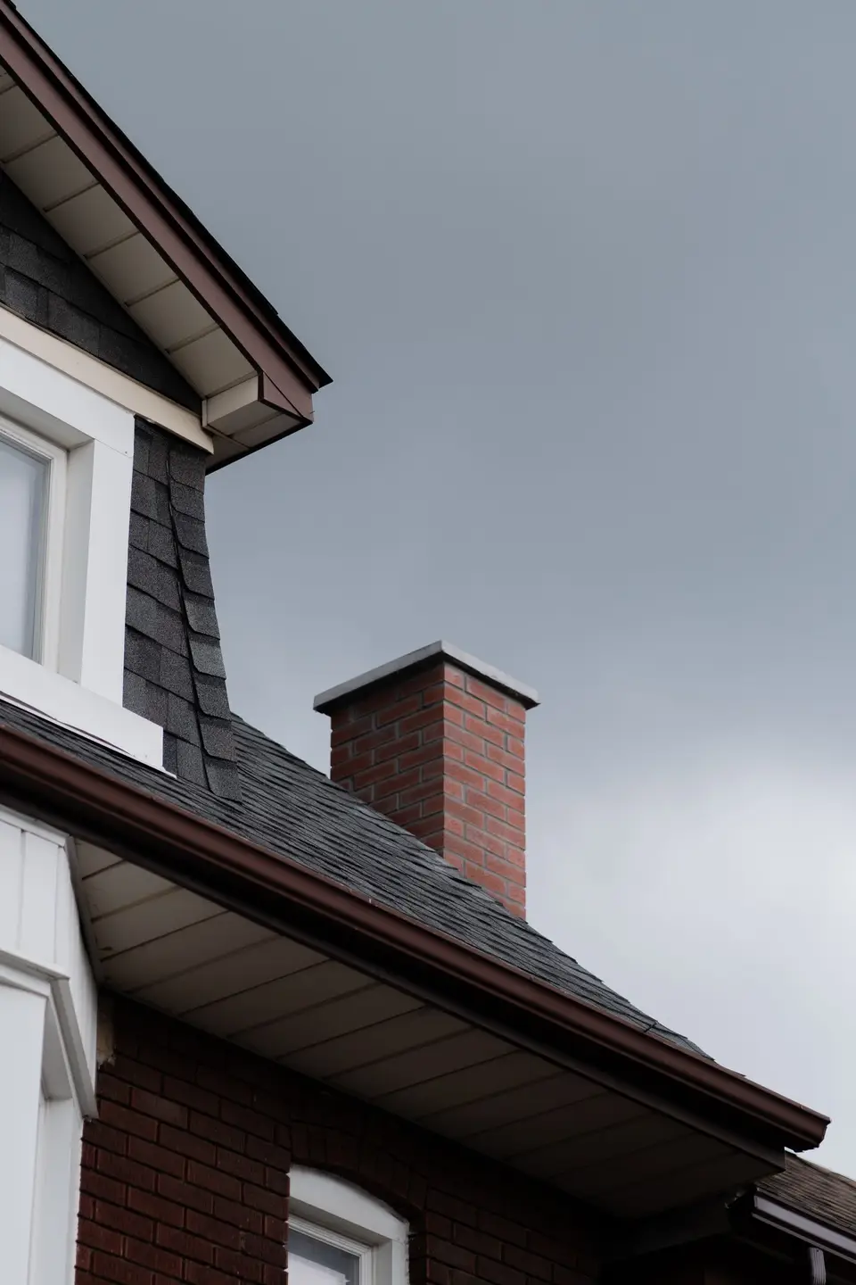Dark shingle roof with a brick chimney