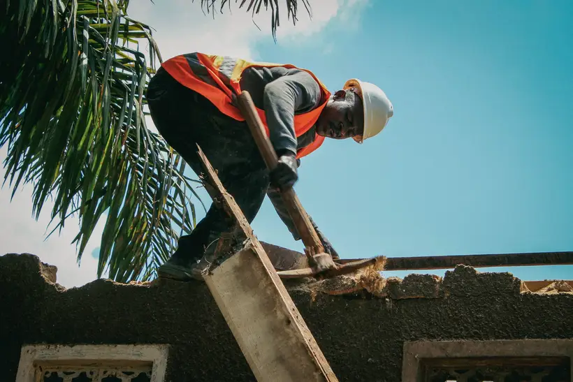 Worker in a hard hat stripping an old roof